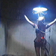A person tied to a wall with an IV drip hangs beneath a bright light and is definitely not in happy place in this scene from V/H/S/94.